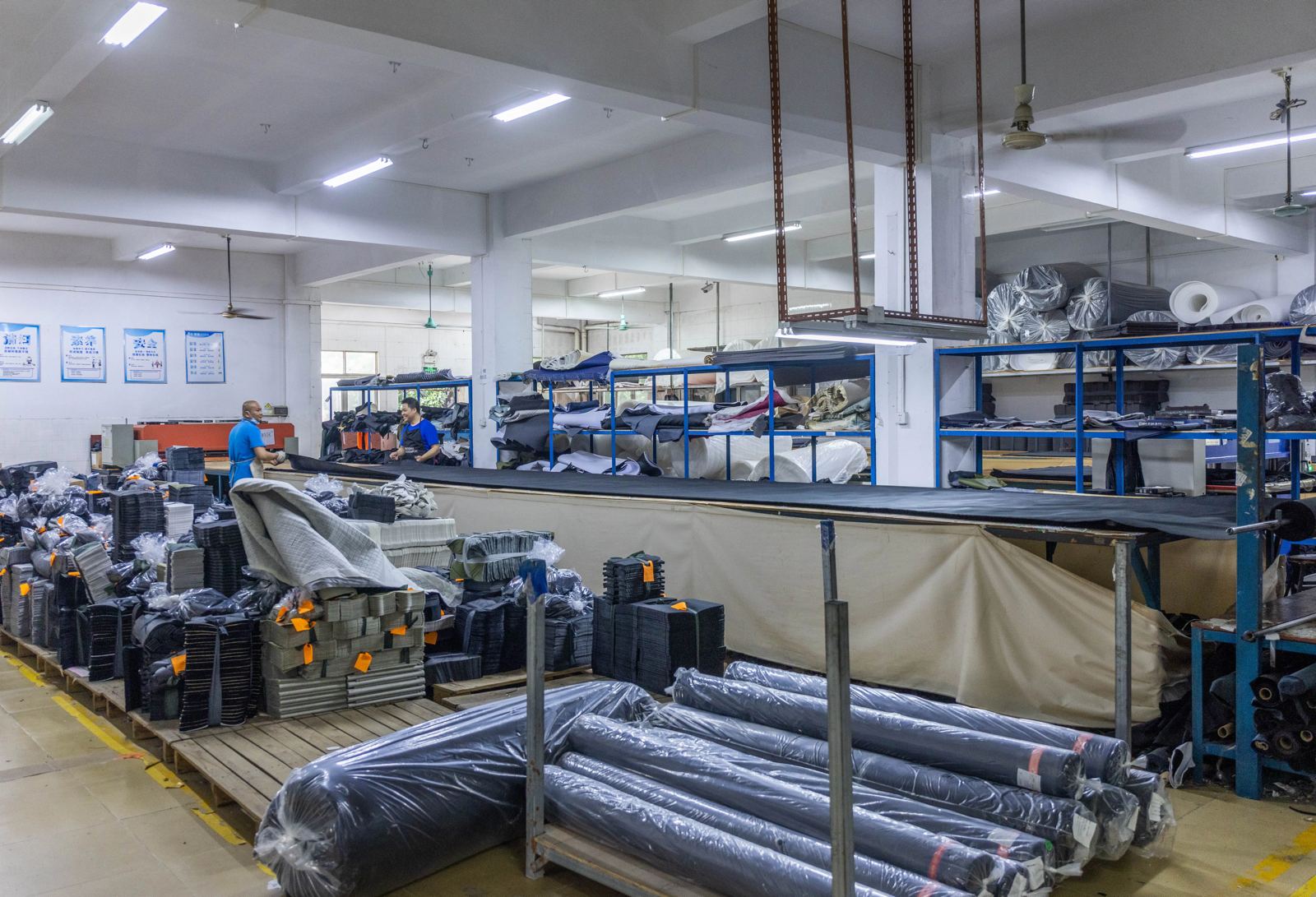 Bag factory preparation area with fabric rolls, cut panels and organized component stacks