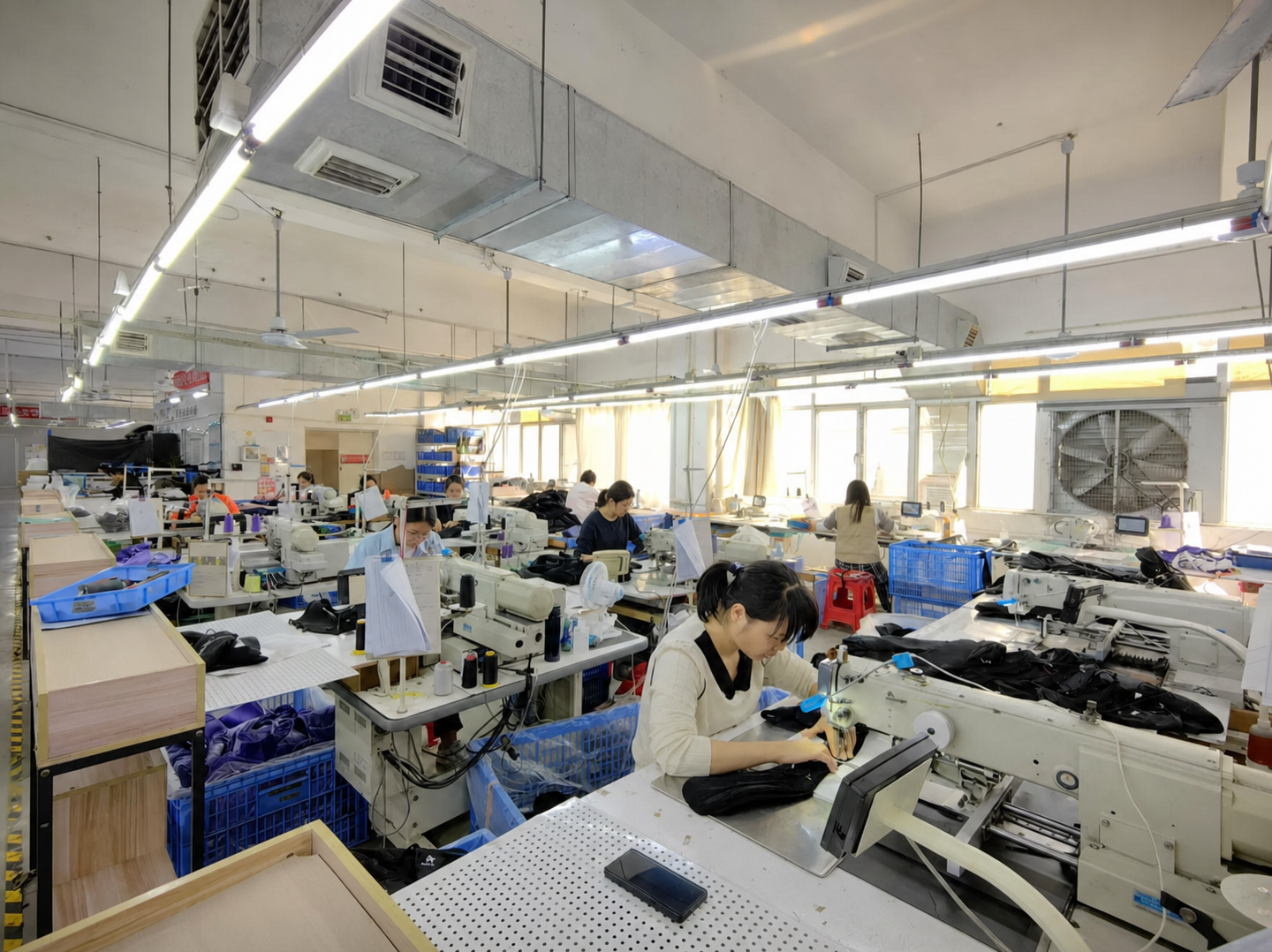 Operators working with black bag panels at industrial sewing stations